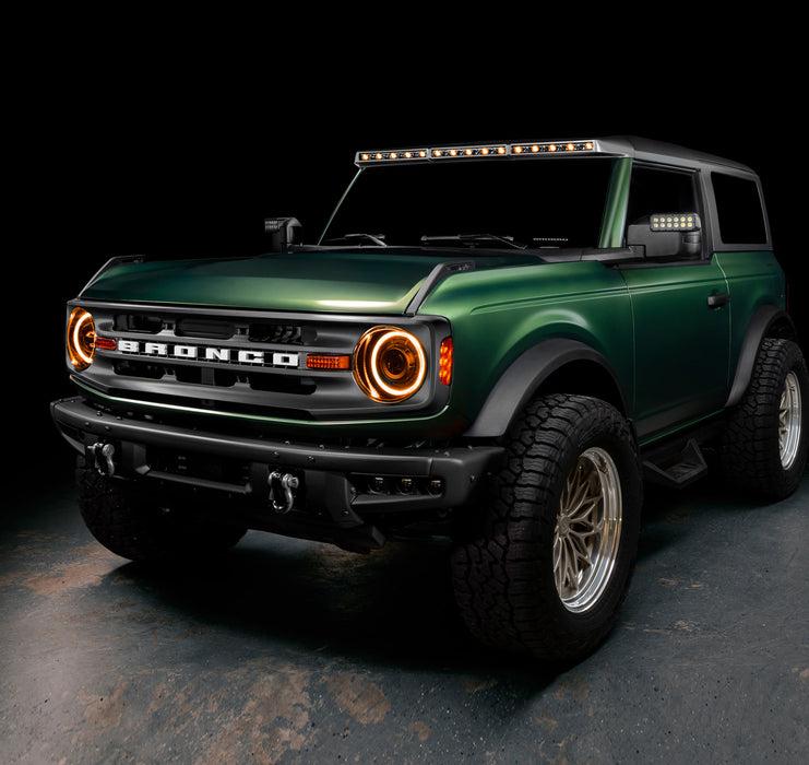 Three quarters view of a green Ford Bronco with multiple ORACLE Lighting products installed, including the Integrated Windshield Roof LED Light Bar System.