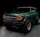 Three quarters view of a green Ford Bronco with multiple ORACLE Lighting products installed, including the Integrated Windshield Roof LED Light Bar System.
