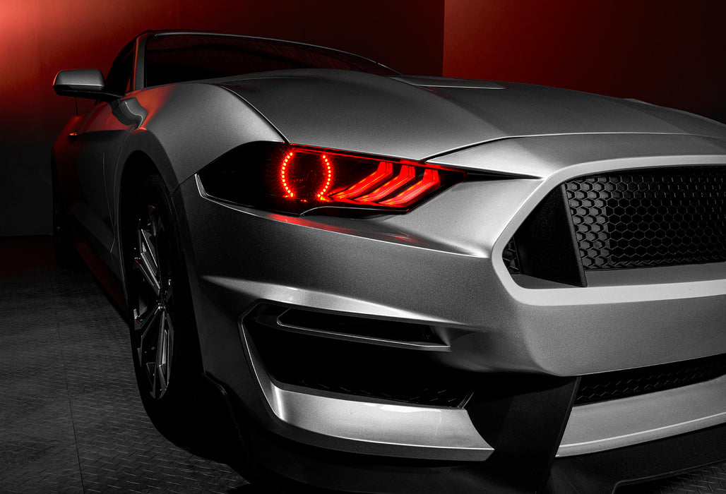 Close-up on a Ford Mustang headlight with red halos and DRLs.