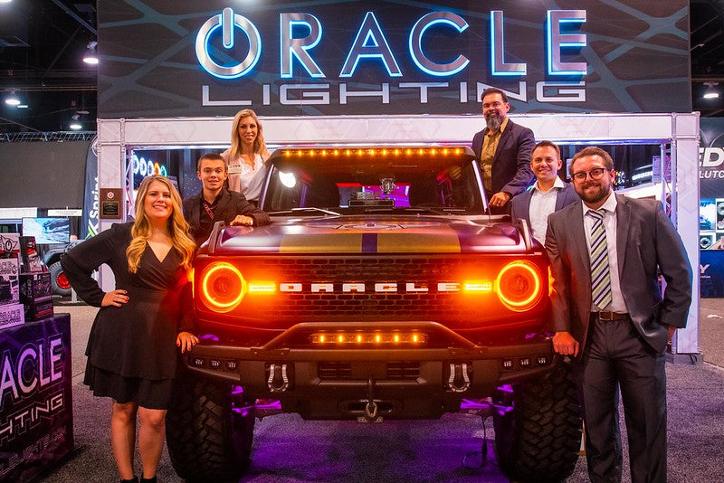 ORACLE Lighting standing around a vehicle while attending SEMA
