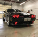 Three quarters view of a black Dodge Challenger with red LED headlight and fog light halo rings installed.