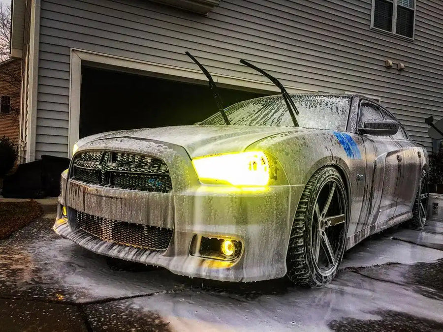 Three quarters view of a Dodge Charger with yellow LED headlight and fog light halo rings installed.