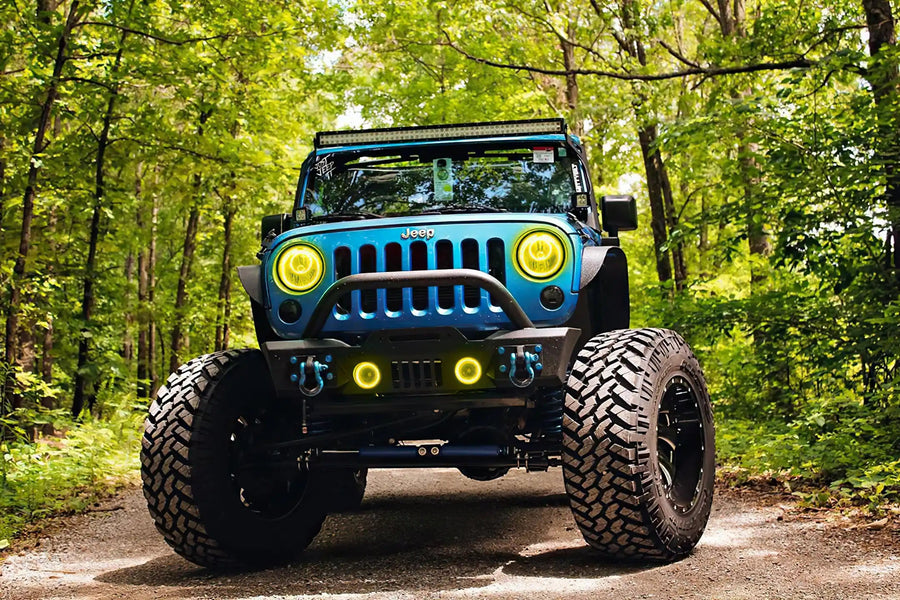 Front end of a Jeep Wrangler JK with yellow LED headlight and fog light halos installed.
