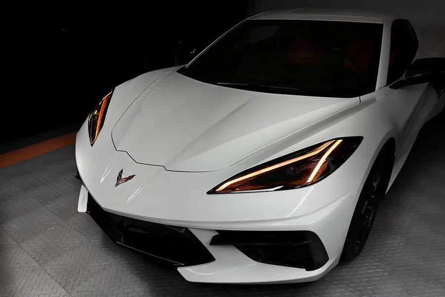Front end of a white C8 Corvette with amber headlight DRLs.