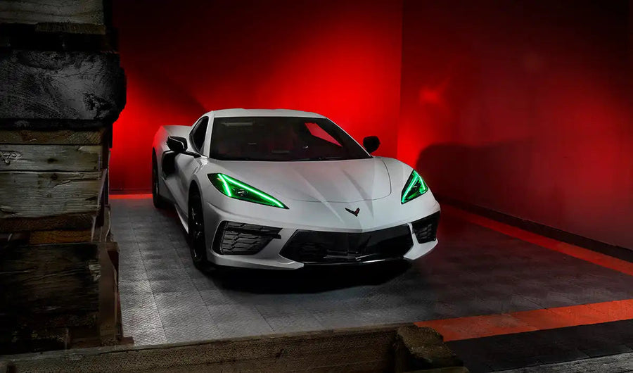 Three quarters view of a white C8 Corvette with green headlight DRLs.