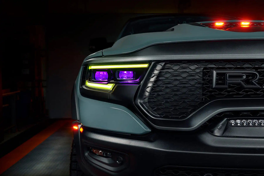 Close-up of Ram 1500 headlights with yellow DRLs and purple demon eye projectors.