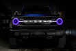 Front view of a blue Ford Bronco with purple halos and DRLs.