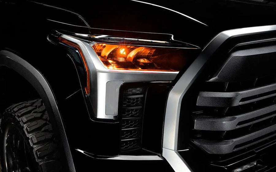 Close-up of a 2022+ Toyota Tundra headlight module installed with amber demon eye projector.