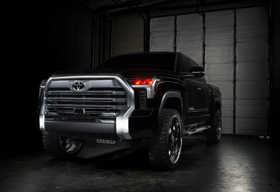 Three quarters view of a black Toyota Tundra with red demon eye projectors.