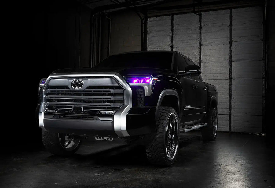 Three quarters view of a black Toyota Tundra with pink demon eye projectors.