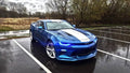 Three quarters view of a blue Chevrolet Camaro with blue headlight and fog light DRLs.