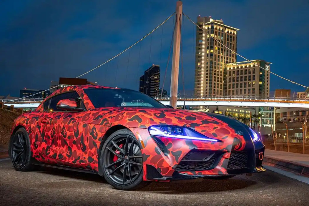 Three quarters view of a wrapped Toyota Supra with blue headlight DRLs.