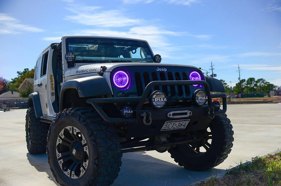 Three quarters view of a Jeep Wrangler JK with purple LED headlight halos installed.