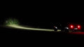 Rear three quarters view of a Jeep showing a beam of light coming from the 7" Multifunction LED Spotlights.