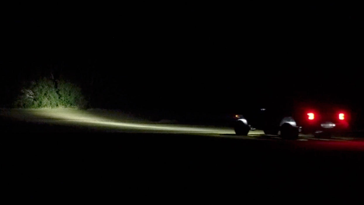 Rear three quarters view of a Jeep showing a beam of light coming from the 7" Multifunction LED Spotlights.