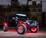 Front three quarters view of a black Jeep with various LED lighting products installed, in front of a warehouse.