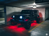 Jeep in a parking garage with red rock lights turned on.