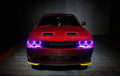 Front end of a red Dodge Challenger with pink halo headlights.