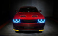 Front end of a red Dodge Challenger with cyan halo headlights.