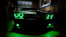 Front end of a Dodge Challenger with green LED headlight halo rings installed.