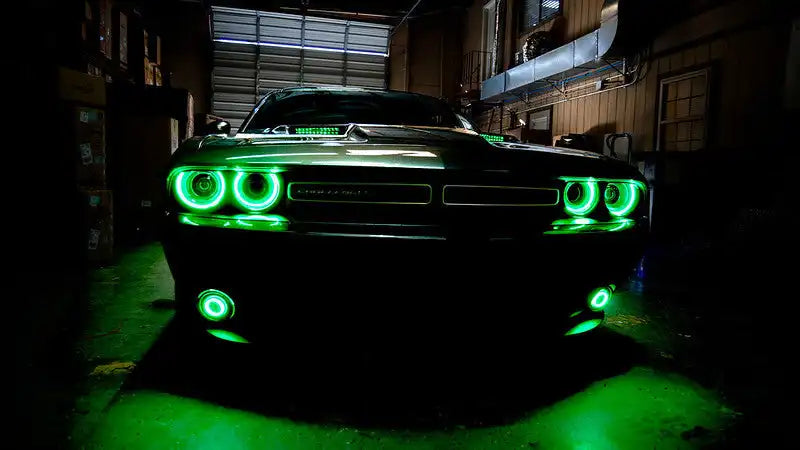 Front end of a Dodge Challenger with green LED headlight halo rings installed.