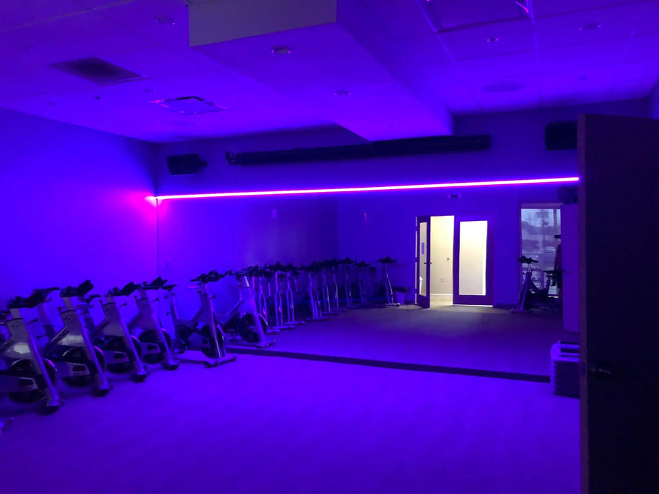 Workout room with purple LED lighting strips above the mirrors.