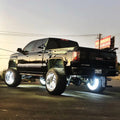 Rear three quarters view of a black GMC Sierra with white LED wheel rings.