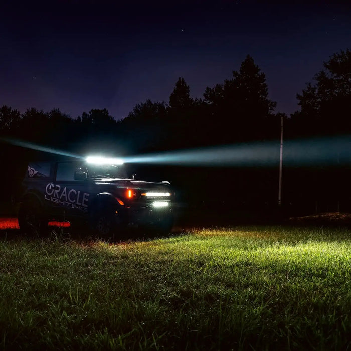 ORACLE Lighting wrapped Ford Bronco in an empty field at night, with a beam of light coming from the Integrated Windshield Roof LED Light Bar System.