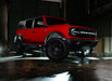 Red Ford Bronco in a garage with white rock lights turned on.