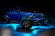 Three quarters view of a blue Jeep Gladiator JT with rock lights set to cyan.