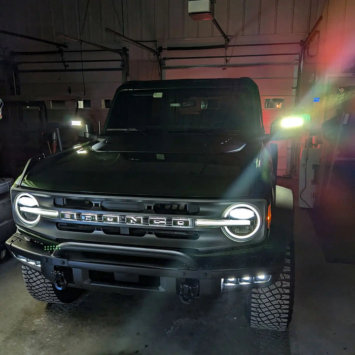 Front view of a green Ford Bronco in a garage with LED Off-Road Side Mirrors turned on.