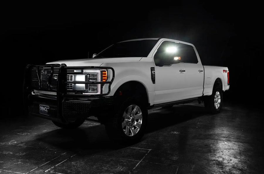 Three quarters view of a white Ford SuperDuty with LED Off-Road Side Mirrors turned on.