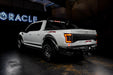 Rear three quarters view of white Ford Raptor with running lights on 