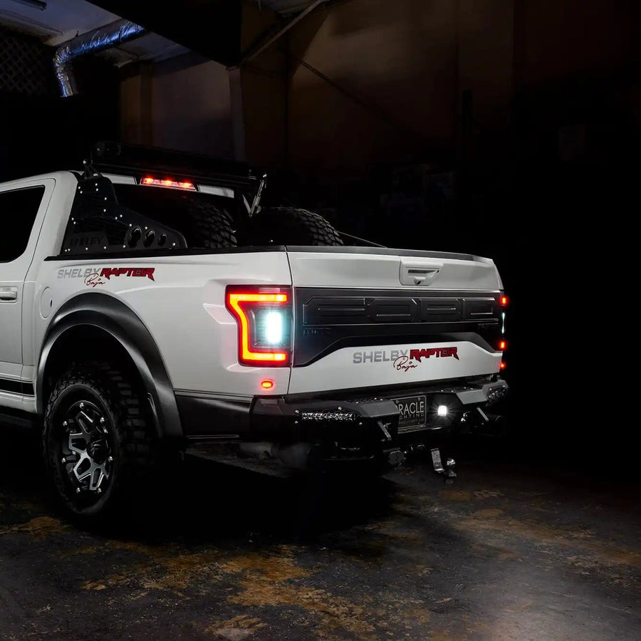 Rear three quarters view of white Ford Raptor with reverse lights on