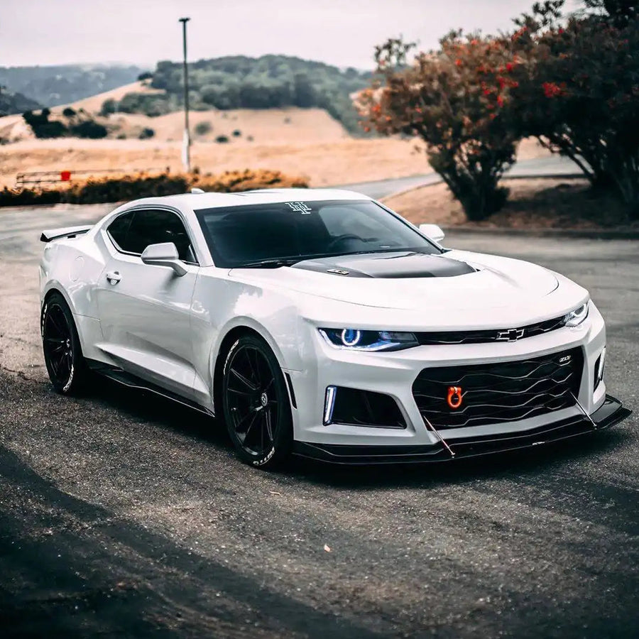 Three quarters view of a white Chevy Camaro with white projector halos.