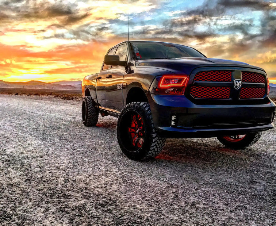 Three quarters view of a black RAM 1500 with red headlight halos.
