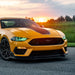 Three quarters view of yellow Ford Mustang with green LED headlights.