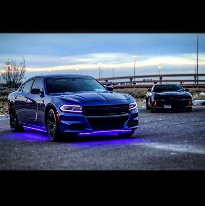 Three quarters view of a blue Dodge Charger with pink headlight DRLs.