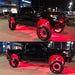2 angles of a black truck with red rock lights and wheel rings installed.
