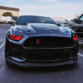 Front end of a black Ford Mustang with red headlight halos and DRLs.