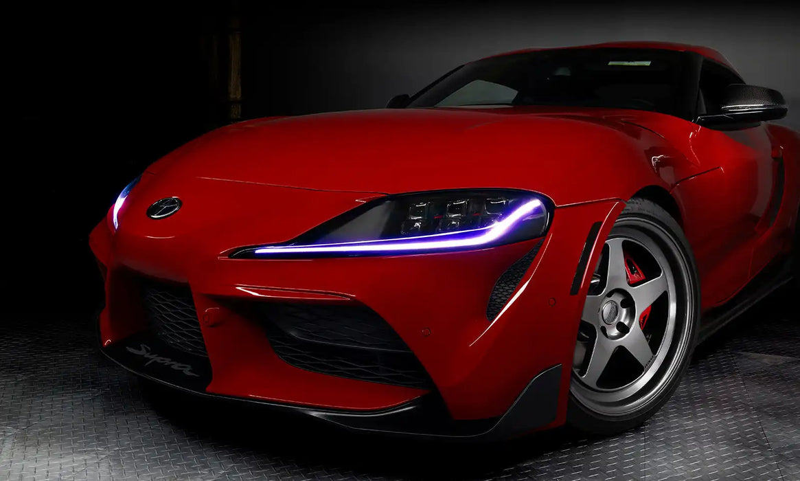 Close-up on the front end of a red Toyota Supra, with purple headlight DRLs.