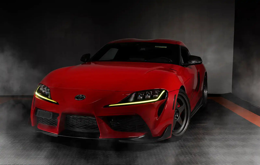 Three quarters view of a red Toyota Supra with yellow headlight DRLs.