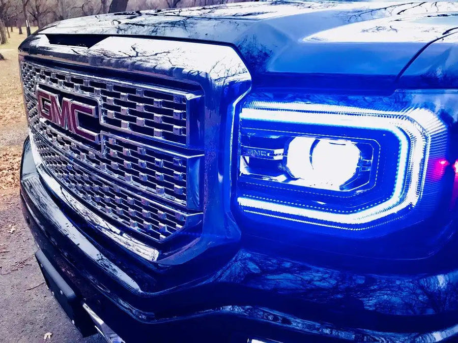 Close-up of a GMC Sierra headlight with blue DRLs.