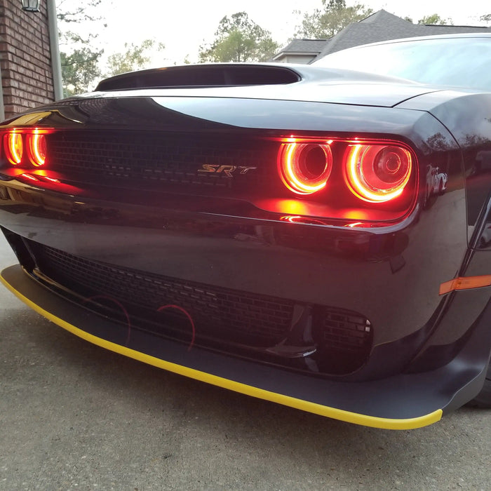 Front end of a black Dodge Challenger with red LED headlight halo rings installed.