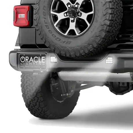 Rear end of a Jeep with ORACLE Lighting Rear Bumper LED Reverse Lights installed, and shining brightly.