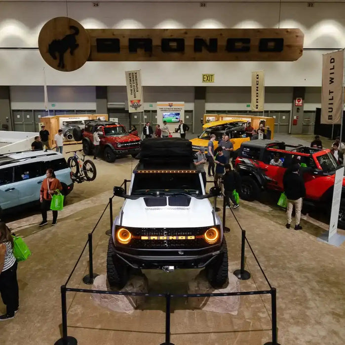 High angled photo of a Bronco showroom. In the center is a white Ford Bronco with Integrated Windshield Roof LED Light Bar System installed.