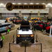 High angled photo of a Bronco showroom. In the center is a white Ford Bronco with Integrated Windshield Roof LED Light Bar System installed.