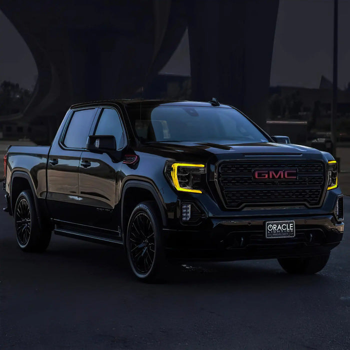 Three quarters view of a black GMC Sierra with yellow headlight DRLs.