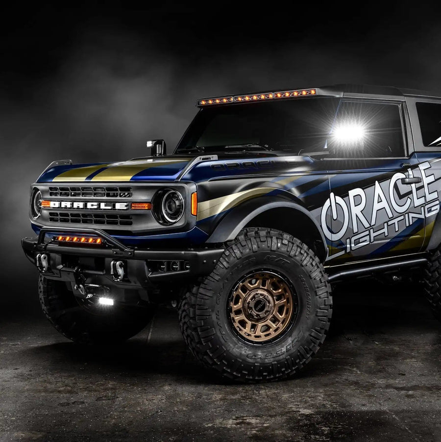 Three quarters view of ORACLE Lighting wrapped Ford Bronco with Integrated Windshield Roof LED Light Bar System installed and set to amber LEDs.