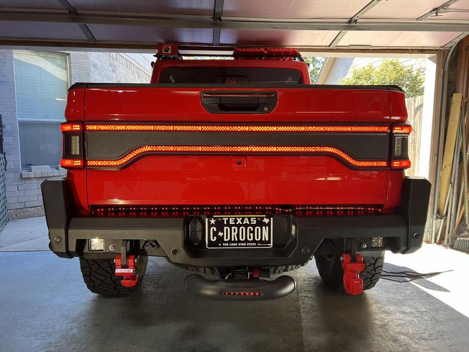 Red Jeep Gladiator in a garage with Racetrack Flush Style LED Tailgate Panel Light installed and DRLs on.
